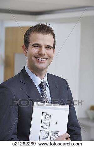 Stock Photo - Male estate agent holding brochure smiling portrait. Fotosearch