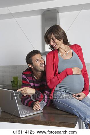 Man and pregnant woman using laptop to shop online in kitchen View Large Photo Image Stock Photography - Man and pregnant woman using laptop to shop online in kitchen. Fotosearch