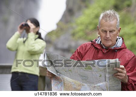 Man and woman in mountains man reading map woman looking through binoculars View Large Photo Image Stock Photograph - Man and woman in mountains man reading map woman looking through binoculars. Fotosearch