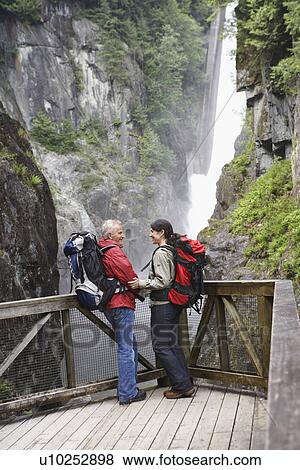 Man and woman in mountains near waterfall looking at each other View Large Photo Image Stock Photo - Man and woman in mountains near waterfall looking at each other. Fotosearch