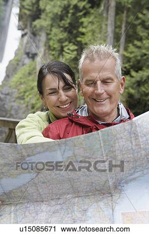 Stock Image - Man and woman reading map waterfall in background. Fotosearch