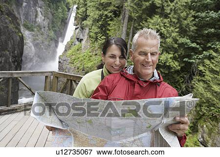 Man and woman reading map waterfall in background View Large Photo Image Stock Photo - Man and woman reading map waterfall in background. Fotosearch
