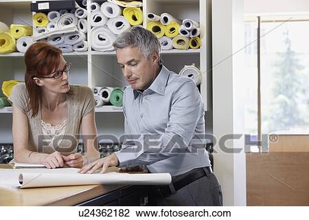 Man and woman studying paperwork in office View Large Photo Image Stock Image - Man and woman studying paperwork in office. Fotosearch