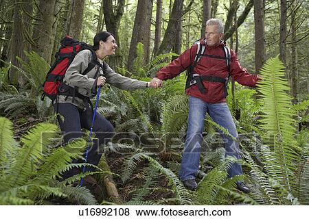 Man and woman walking in forest carrying backpacks holding hands View Large Photo Image Stock Photo - Man and woman walking in forest carrying backpacks holding hands. Fotosearch