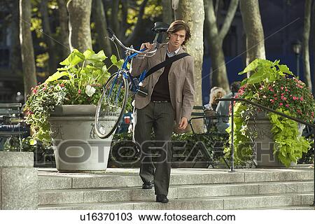 Man carrying bicycle down steps in park View Large Photo Image Stock Image - Man carrying bicycle down steps in park. Fotosearch