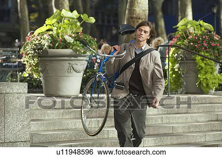 Stock Photograph - Man carrying bicycle down steps in park. Fotosearch