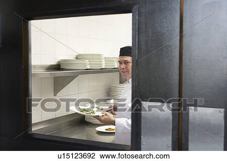 Man chef holding plates of food in kitchen View Large Photo Image Stock Image - Man chef holding plates of food in kitchen. Fotosearch