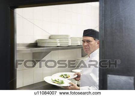 Man chef holding plates of food in kitchen View Large Photo Image Stock Photo - Man chef holding plates of food in kitchen. Fotosearch