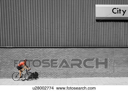 Man cycling past building with 'City' written on side View Large Photo Image Picture - Man cycling past building with 'City' written on side. Fotosearch