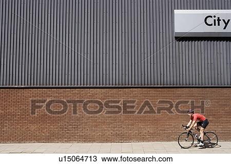 Man cycling past building with 'City' written on side View Large Photo Image Stock Image - Man cycling past building with 'City' written on side. Fotosearch