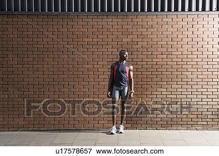 Man in sports clothing standing in front of wall View Large Photo Image Stock Photo - Man in sports clothing standing in front of wall. Fotosearch