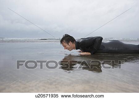 Man in wetsuit doing pushups in shallow water on beach side view View Large Photo Image Stock Photography - Man in wetsuit doing pushups in shallow water on beach side view. Fotosearch