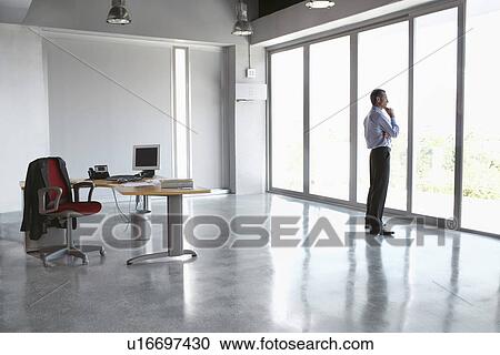 Man looking out of window in empty office building View Large Photo Image Stock Image - Man looking out of window in empty office building. Fotosearch