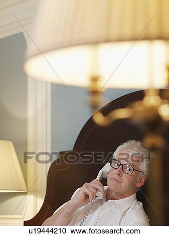 Man lying on bed using phone View Large Photo Image Stock Image - Man lying on bed using phone. Fotosearch