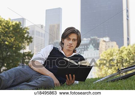Man lying on lawn holding book portrait View Large Photo Image Stock Image - Man lying on lawn holding book portrait. Fotosearch