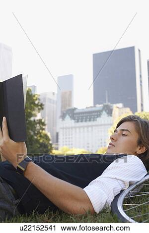 Man lying on lawn reading book close-up View Large Photo Image Stock Image - Man lying on lawn reading book close-up. Fotosearch