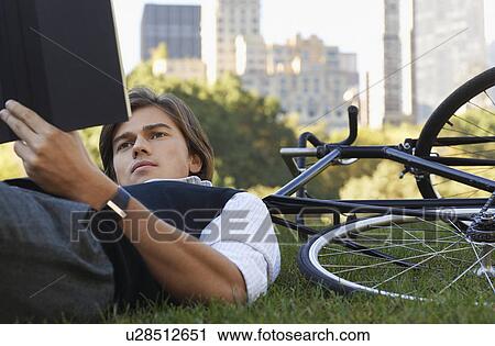 Man lying on lawn reading book close-up View Large Photo Image Stock Image - Man lying on lawn reading book close-up. Fotosearch