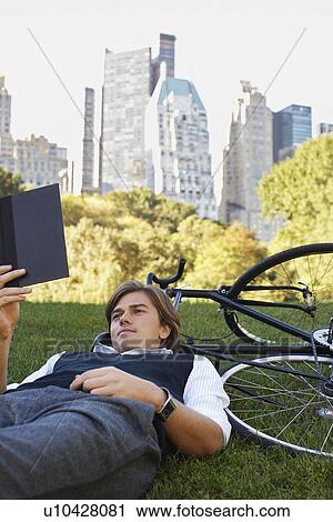 Man lying on lawn reading book View Large Photo Image Stock Image - Man lying on lawn reading book. Fotosearch