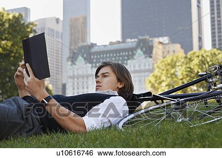 Man lying on lawn reading book View Large Photo Image Stock Photograph - Man lying on lawn reading book. Fotosearch