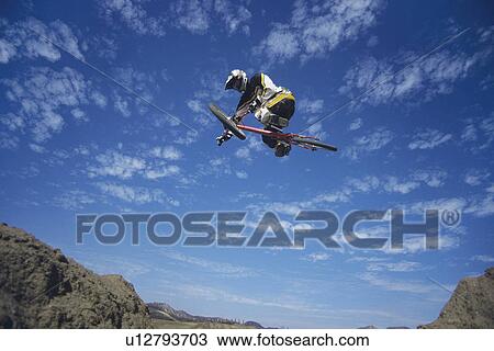 Man on mountain bike jumping low angle view View Large Photo Image Stock Image - Man on mountain bike jumping low angle view. Fotosearch