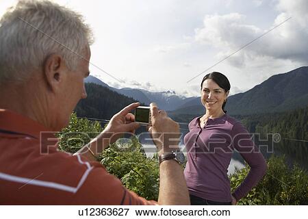 Man photographing woman mountains in background View Large Photo Image Stock Photo - Man photographing woman mountains in background. Fotosearch