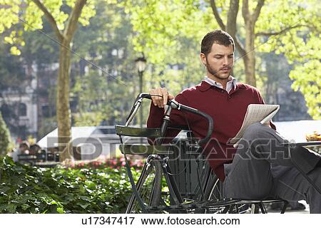 Stock Photo - Man reading newspaper in park. Fotosearch