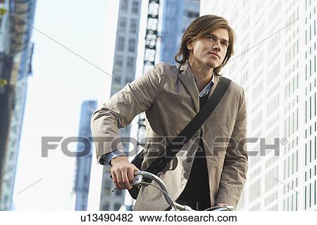 Stock Image - Man riding bicycle in downtown district low angle view. Fotosearch