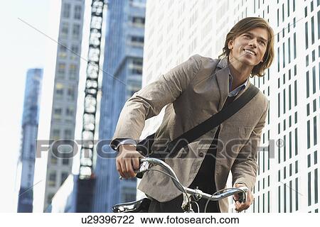 Man riding bicycle in downtown district low angle view View Large Photo Image Stock Image - Man riding bicycle in downtown district low angle view. Fotosearch