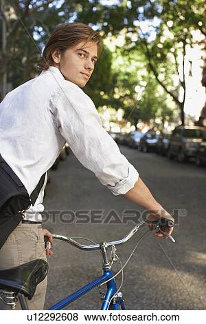 Stock Photo - Man riding bicycle in residential district close-up. Fotosearch