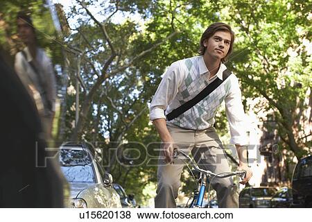 Stock Photo - Man riding bicycle in residential district. Fotosearch