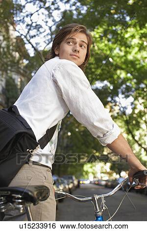 Stock Photograph - Man riding bicycle in residential district close-up. Fotosearch