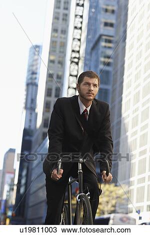 Stock Image - Man riding bicycle on street low angle view. Fotosearch