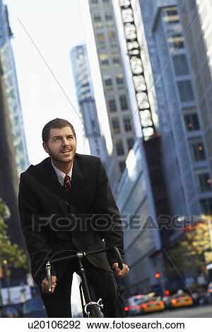 Stock Image - Man riding bicycle on street low angle view. Fotosearch