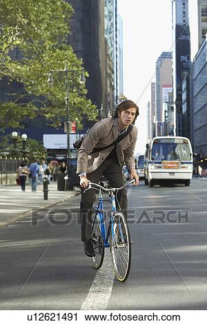 Man riding bicycle on street View Large Photo Image Stock Image - Man riding bicycle on street. Fotosearch