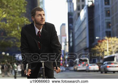Stock Image - Man riding bicycle on street. Fotosearch