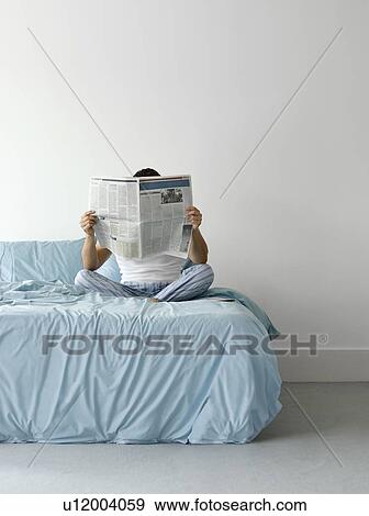Man sitting on bed reading newspaper View Large Photo Image Stock Photo - Man sitting on bed reading newspaper. Fotosearch