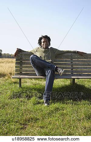 Man sitting on bench in field View Large Photo Image Stock Photography - Man sitting on bench in field. Fotosearch