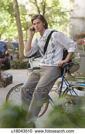 Man sitting on bicycle talking on mobile phone View Large Photo Image Stock Image - Man sitting on bicycle talking on mobile phone. Fotosearch
