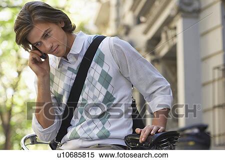 Man sitting on bicycle talking on mobile phone View Large Photo Image Stock Photography - Man sitting on bicycle talking on mobile phone. Fotosearch