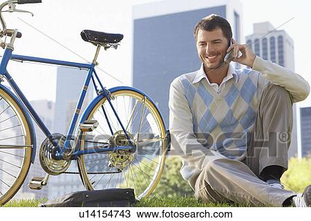 Man sitting on lawn in park talking on mobile phone View Large Photo Image Stock Image - Man sitting on lawn in park talking on mobile phone. Fotosearch