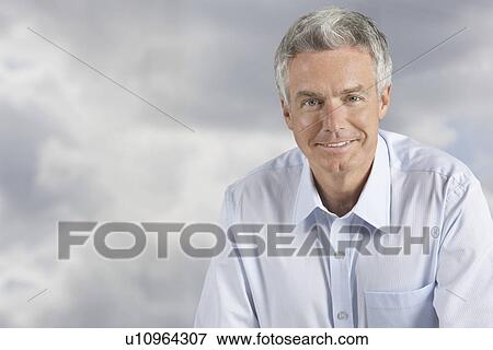 Stock Photo - Man smiling in front of clouds portrait. Fotosearch