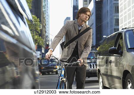 Man standing by bicycle on busy street View Large Photo Image Stock Image - Man standing by bicycle on busy street. Fotosearch