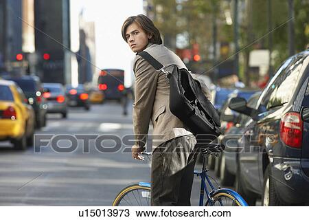 Man standing by bicycle on busy street View Large Photo Image Stock Image - Man standing by bicycle on busy street. Fotosearch