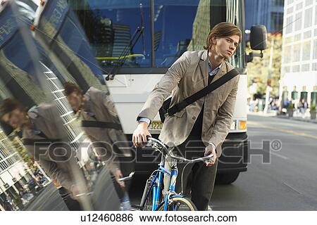 Man standing by bicycle on busy street View Large Photo Image Stock Photograph - Man standing by bicycle on busy street. Fotosearch