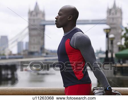 Stock Photo - Man stretching in front of Tower Bridge England London. Fotosearch