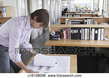 Man studying blueprint in office View Large Photo Image Stock Photograph - Man studying blueprint in office. Fotosearch
