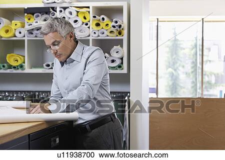 Stock Image - Man studying paperwork in office. Fotosearch