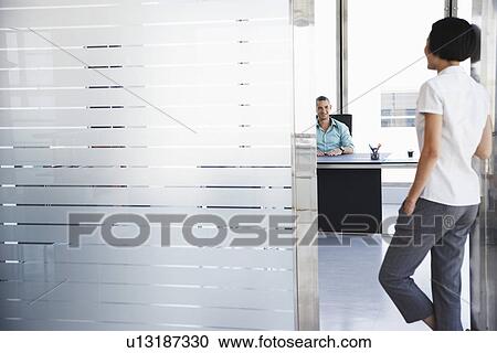 Man talking to woman standing in doorway of his office View Large Photo Image Stock Image - Man talking to woman standing in doorway of his office. Fotosearch