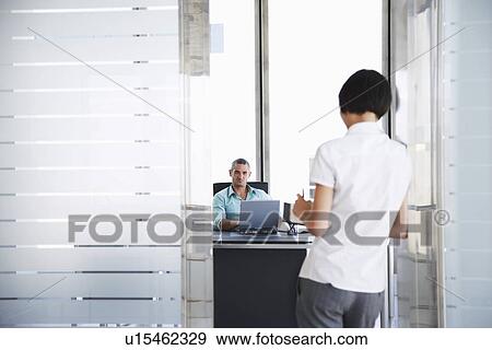 Stock Photo - Man talking to woman standing in doorway of his office. Fotosearch
