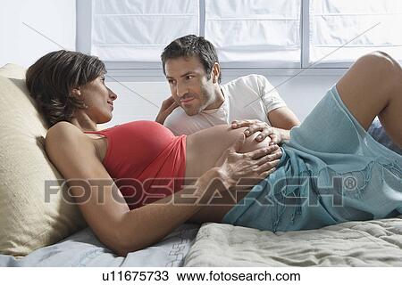 Man touching stomach of pregnant woman lying in bed in bedroom View Large Photo Image Stock Image - Man touching stomach of pregnant woman lying in bed in bedroom. Fotosearch